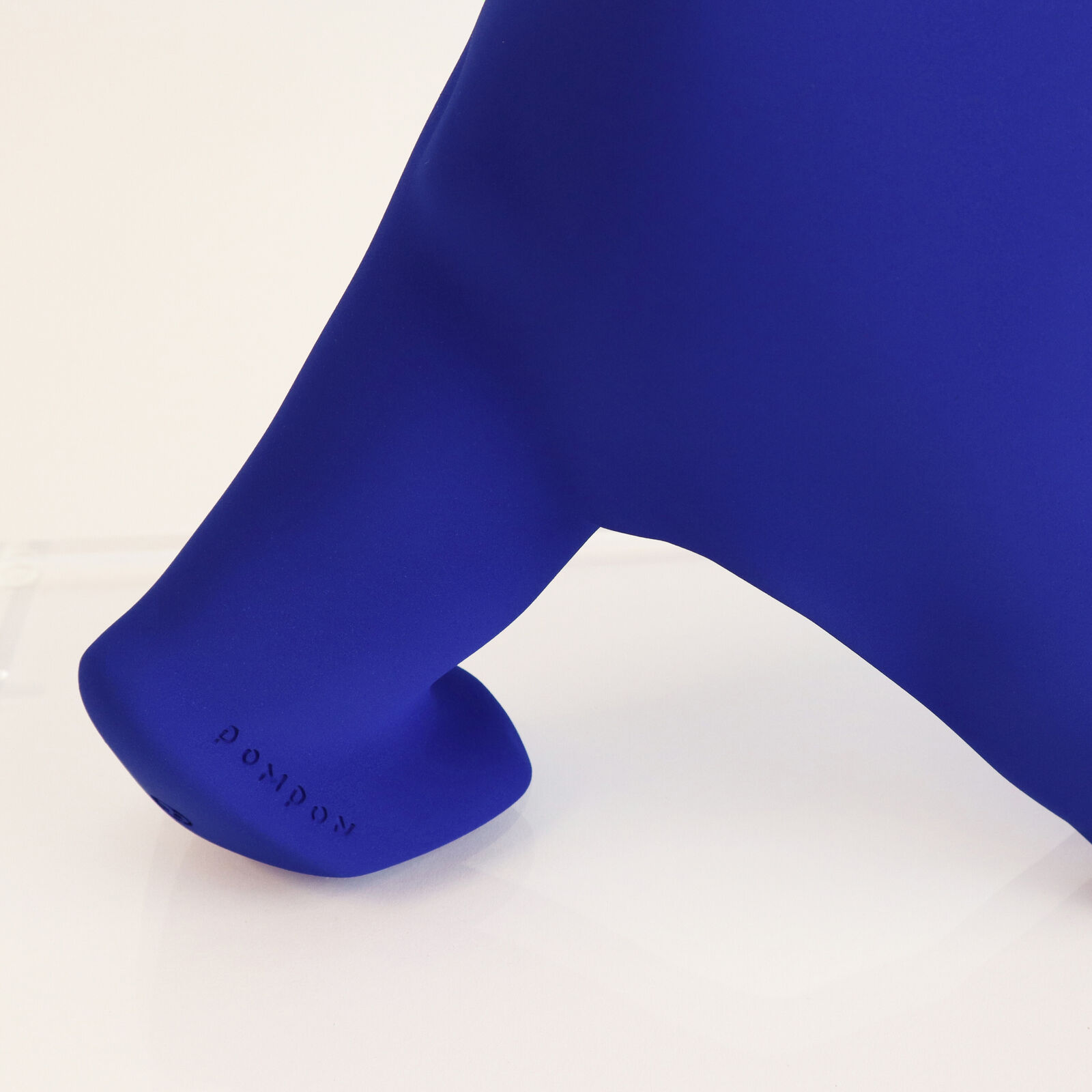 A smooth, matte blue sculpture of a four-legged animal in a walking pose.