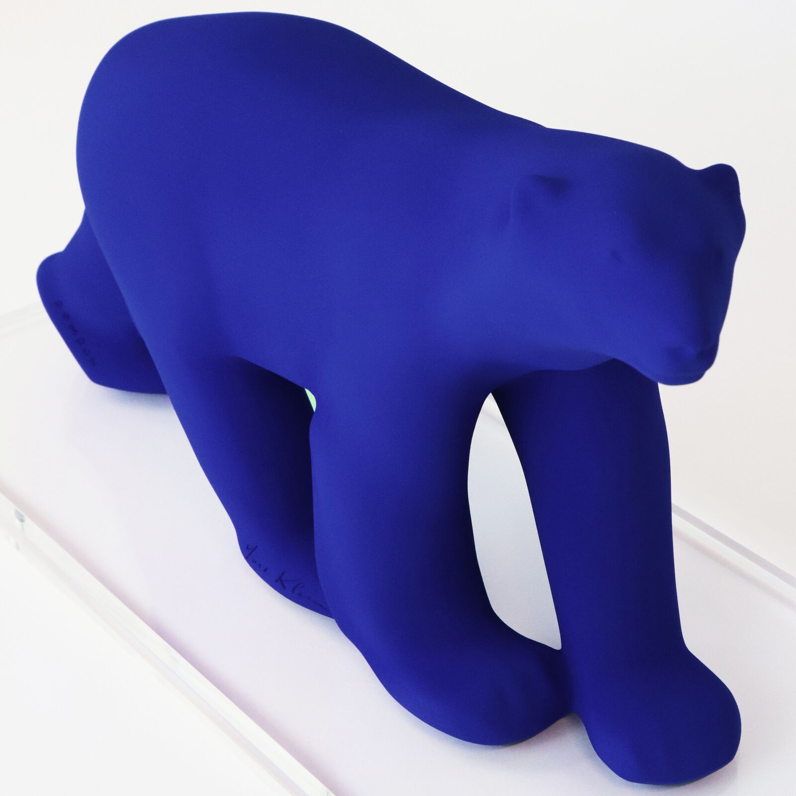 A smooth, matte blue sculpture of a four-legged animal in a walking pose.