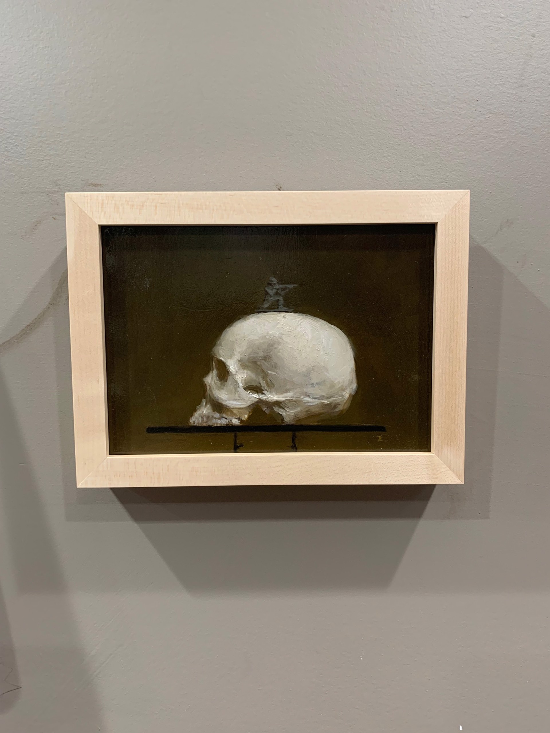 A painting of a human skull on a shelf with a statue on top.