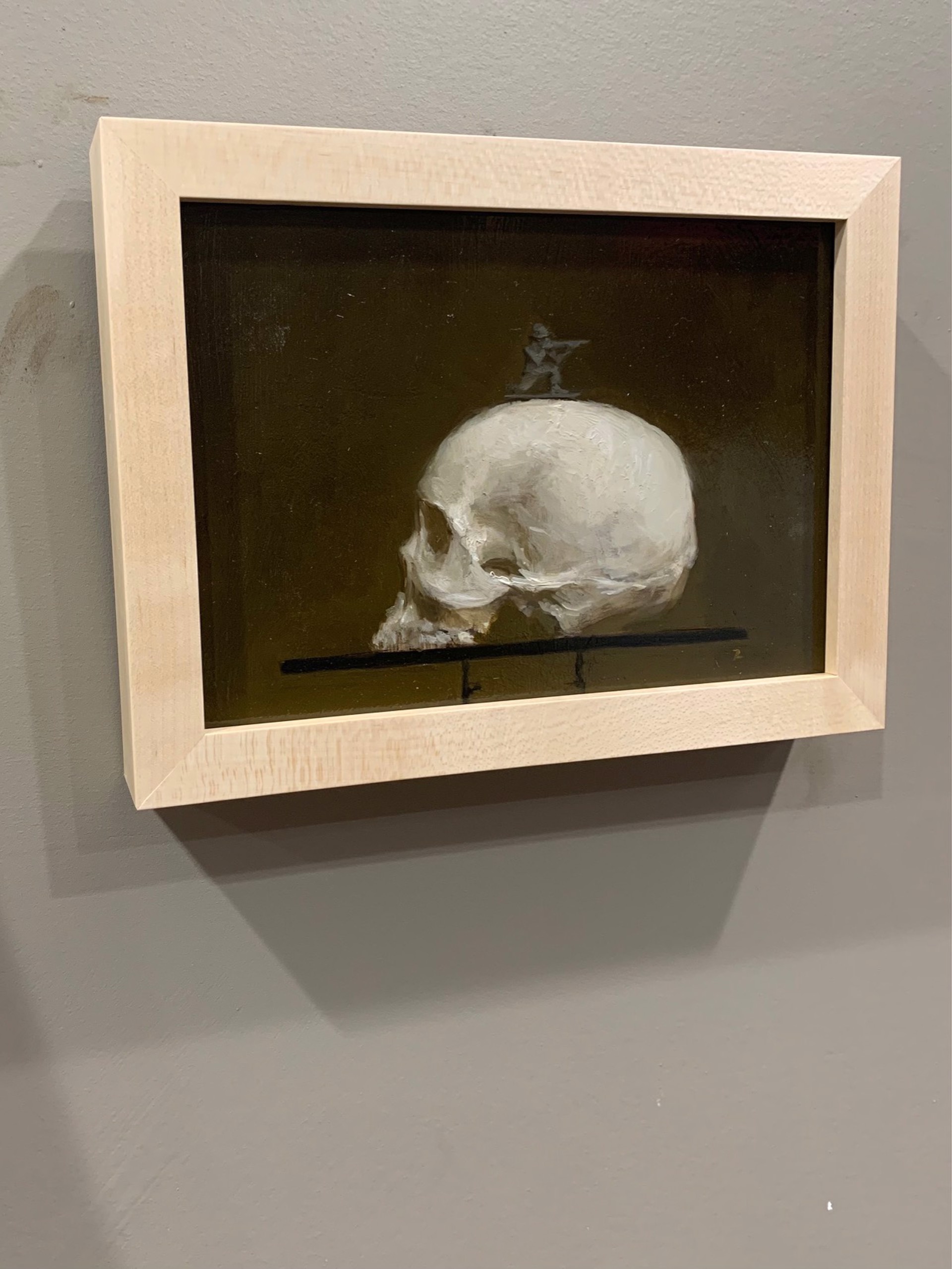 A painting of a human skull on a shelf with a statue on top.