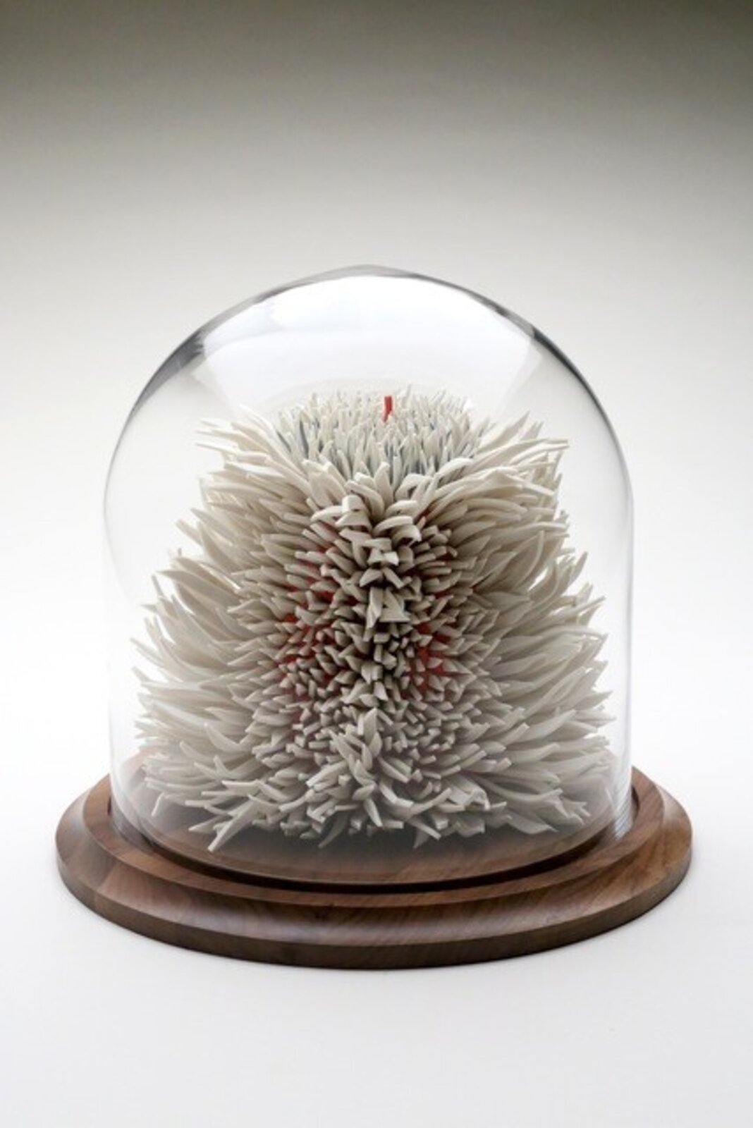 A spiky, spherical sculpture made of layered white and grey elements with hints of red.