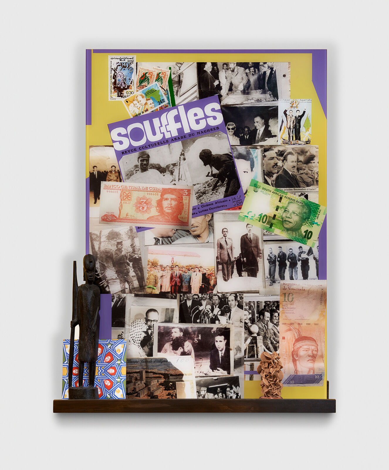 A collage of various pictures on a wall with a statue of a man.