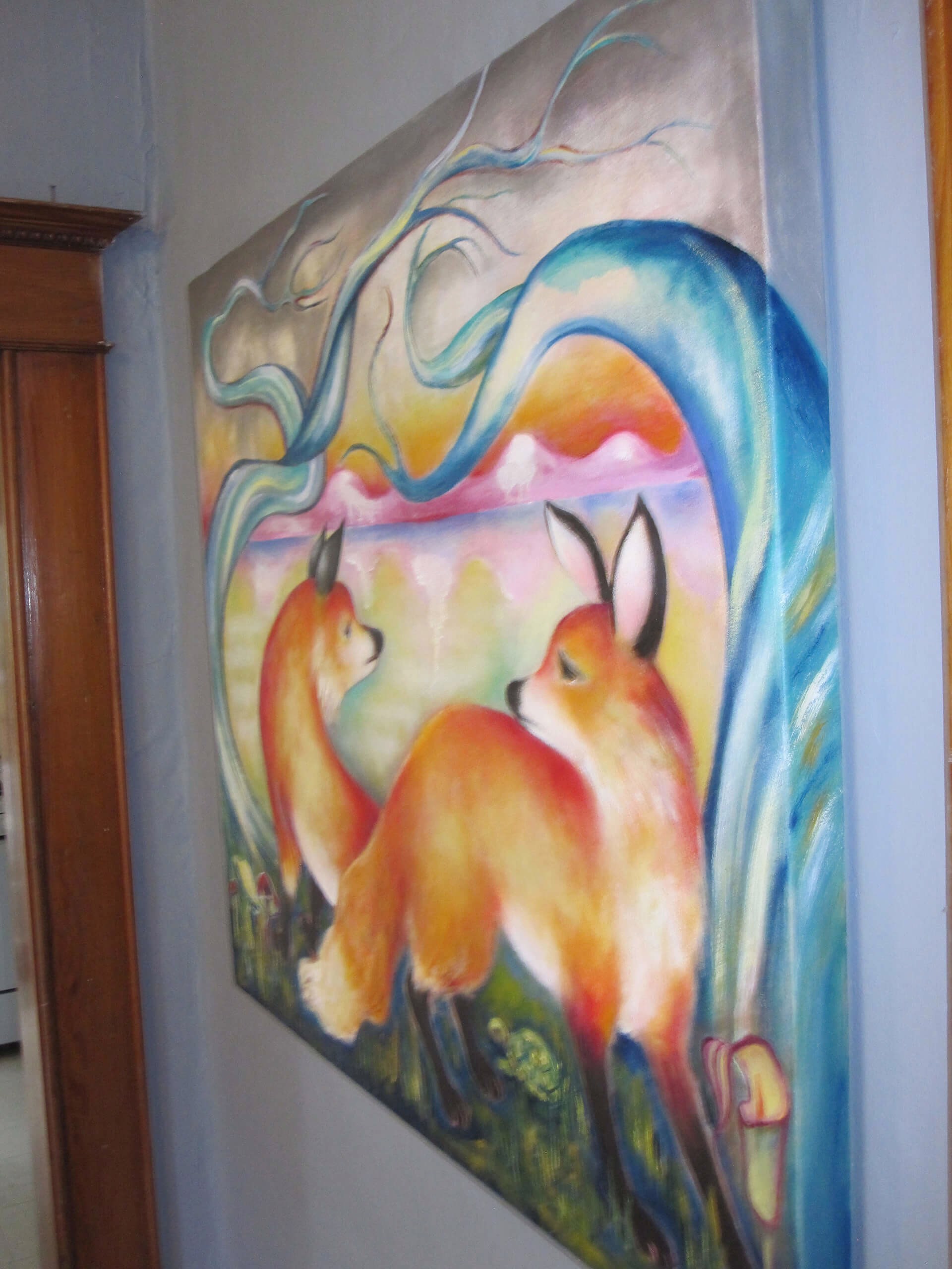 A painting of two foxes in a field of grass and trees.