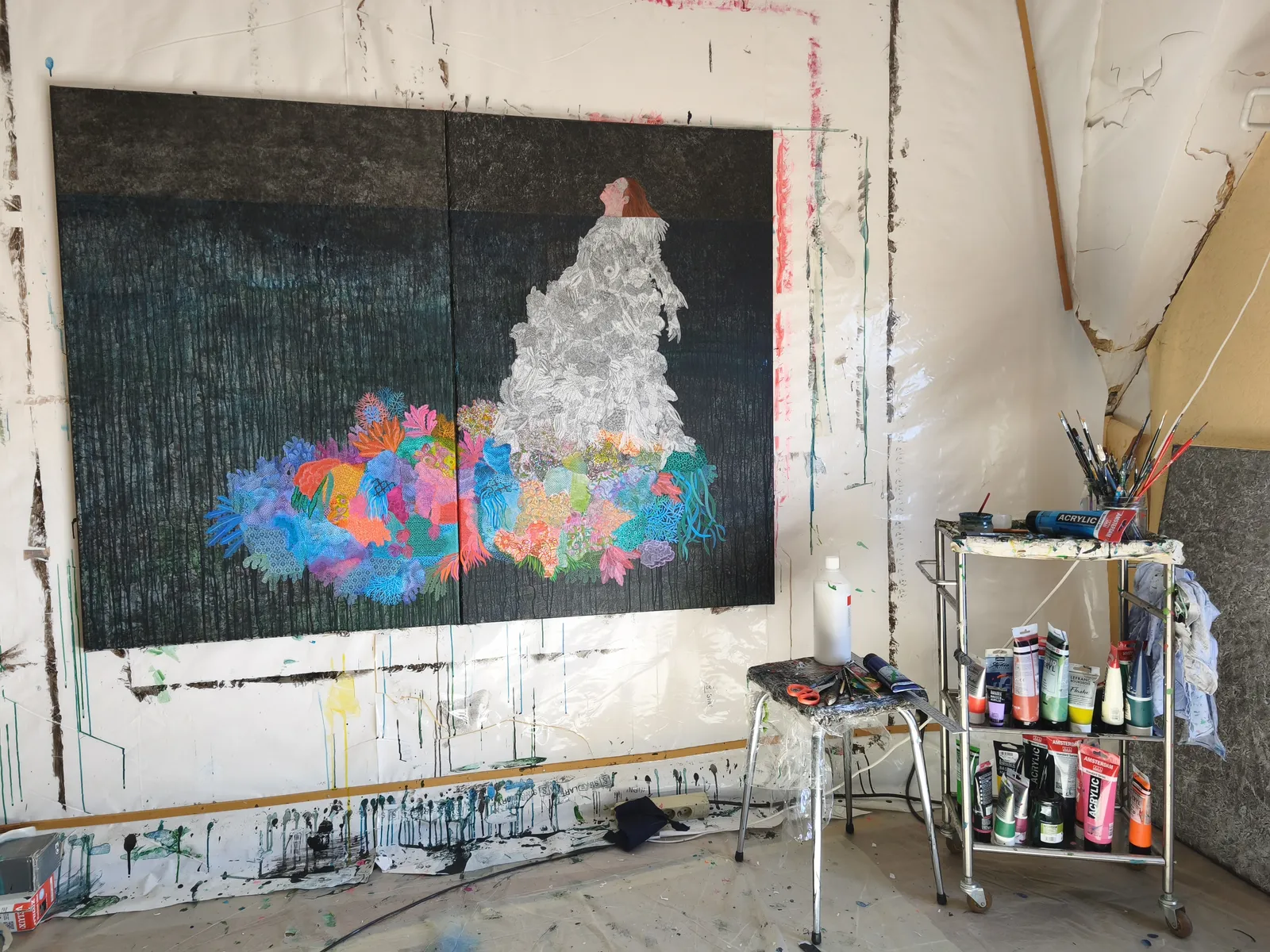 A figure in a white dress stands against a dark background, surrounded by a vibrant explosion of colorful coral-like shapes.