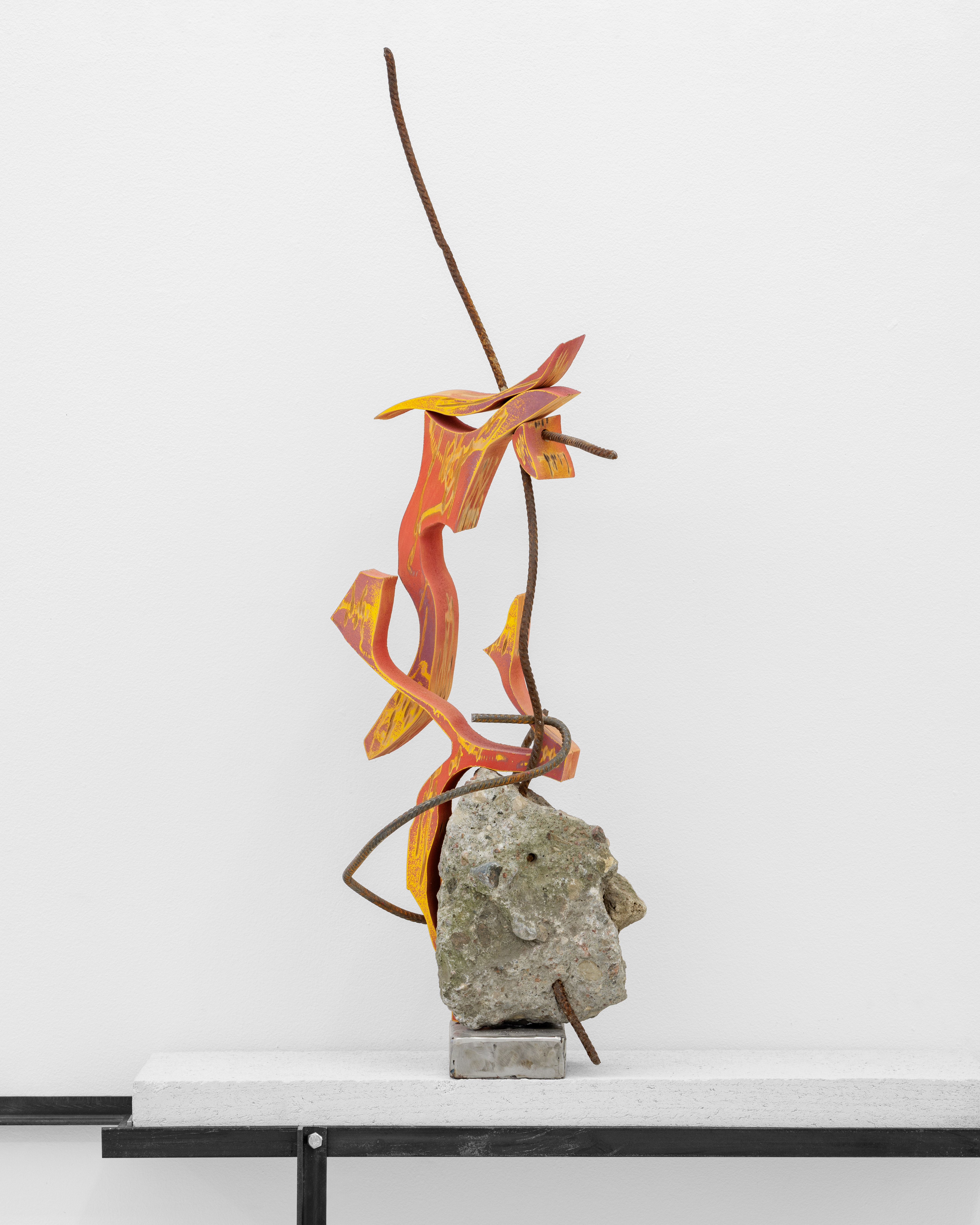 A metal sculpture on top of a rock on a shelf.