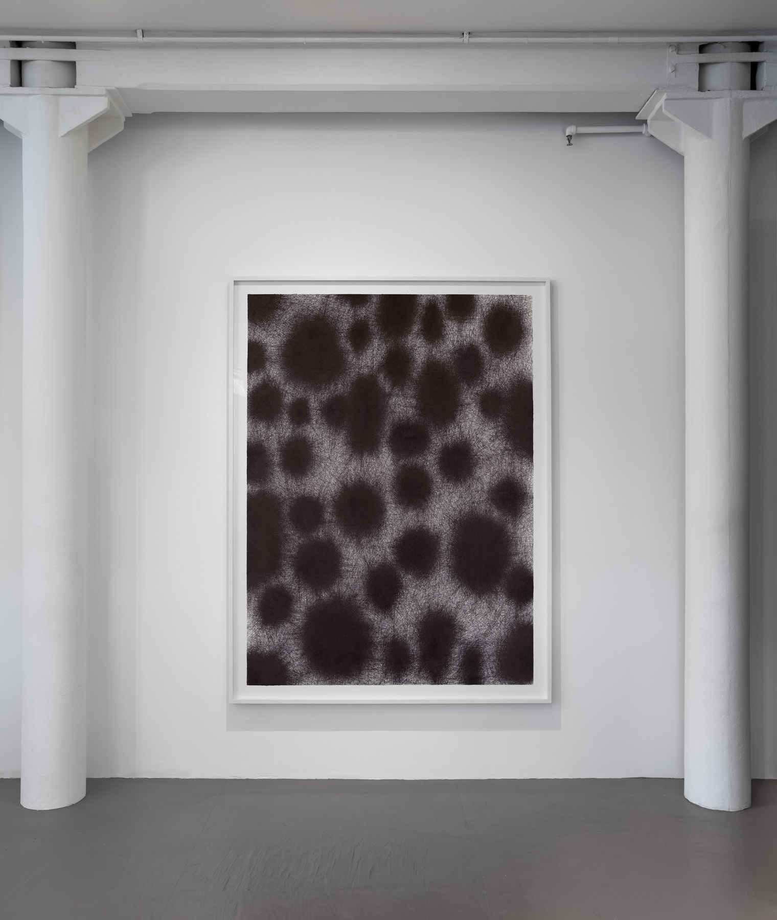A monochromatic abstract composition featuring dark, textured circles on a light background.