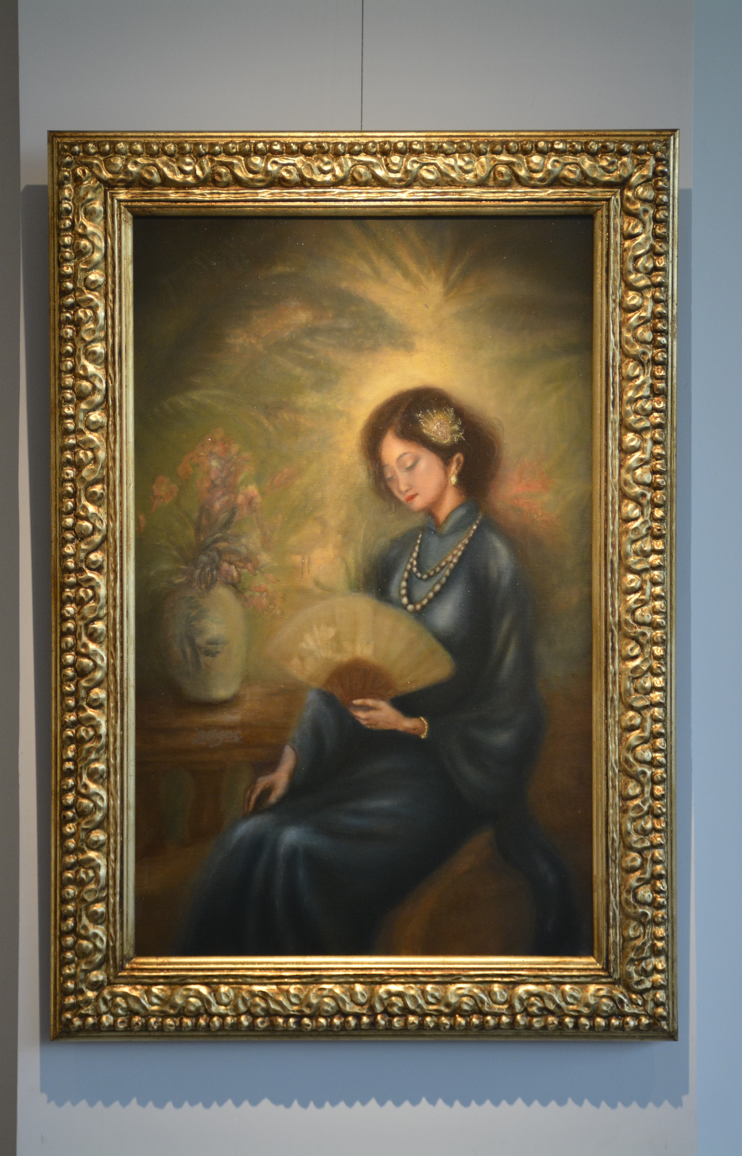 A serene portrait of a seated figure in a blue dress holding a fan, illuminated by a radiant golden glow.