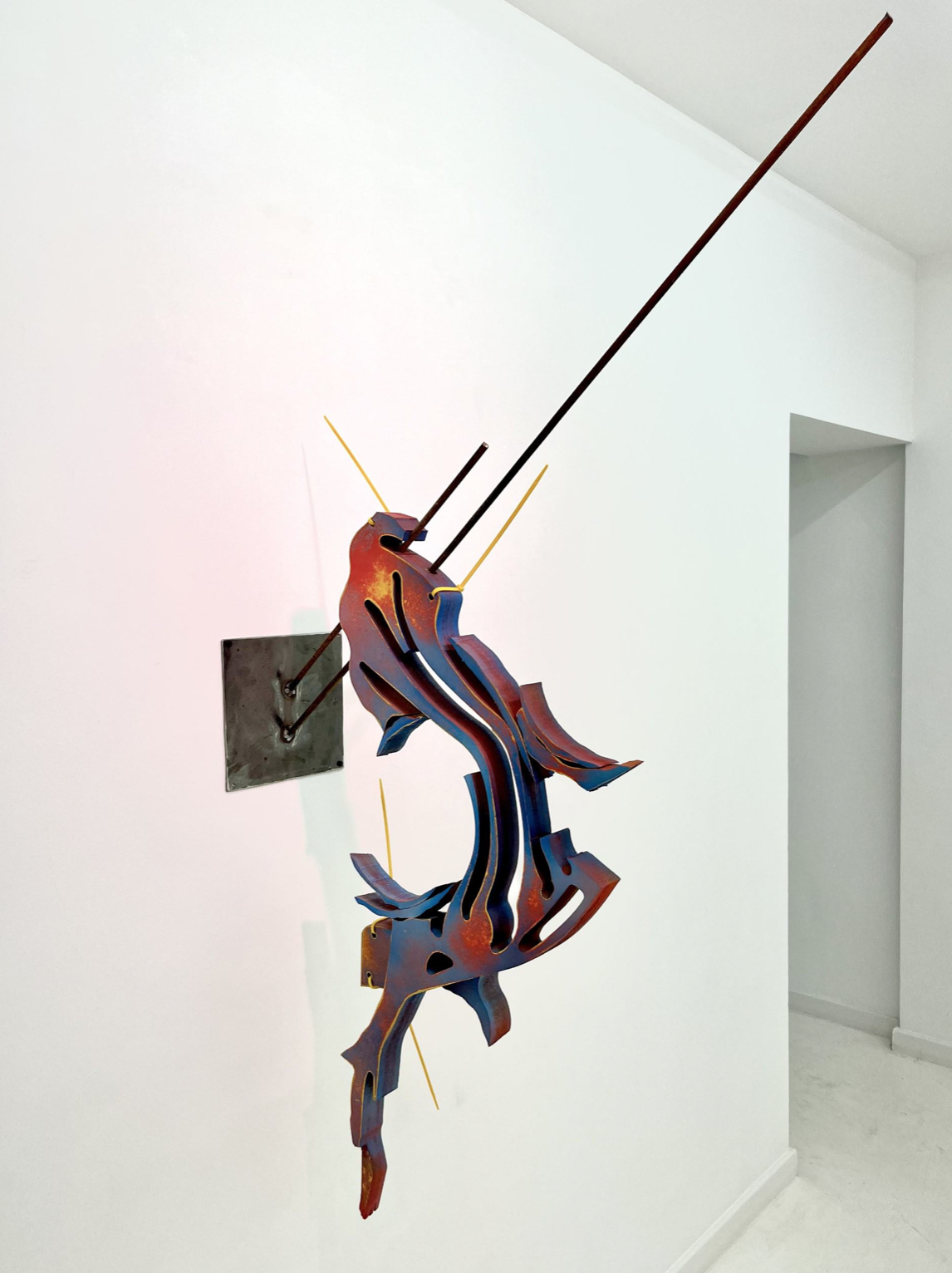 A metal sculpture on a wall in a white room.