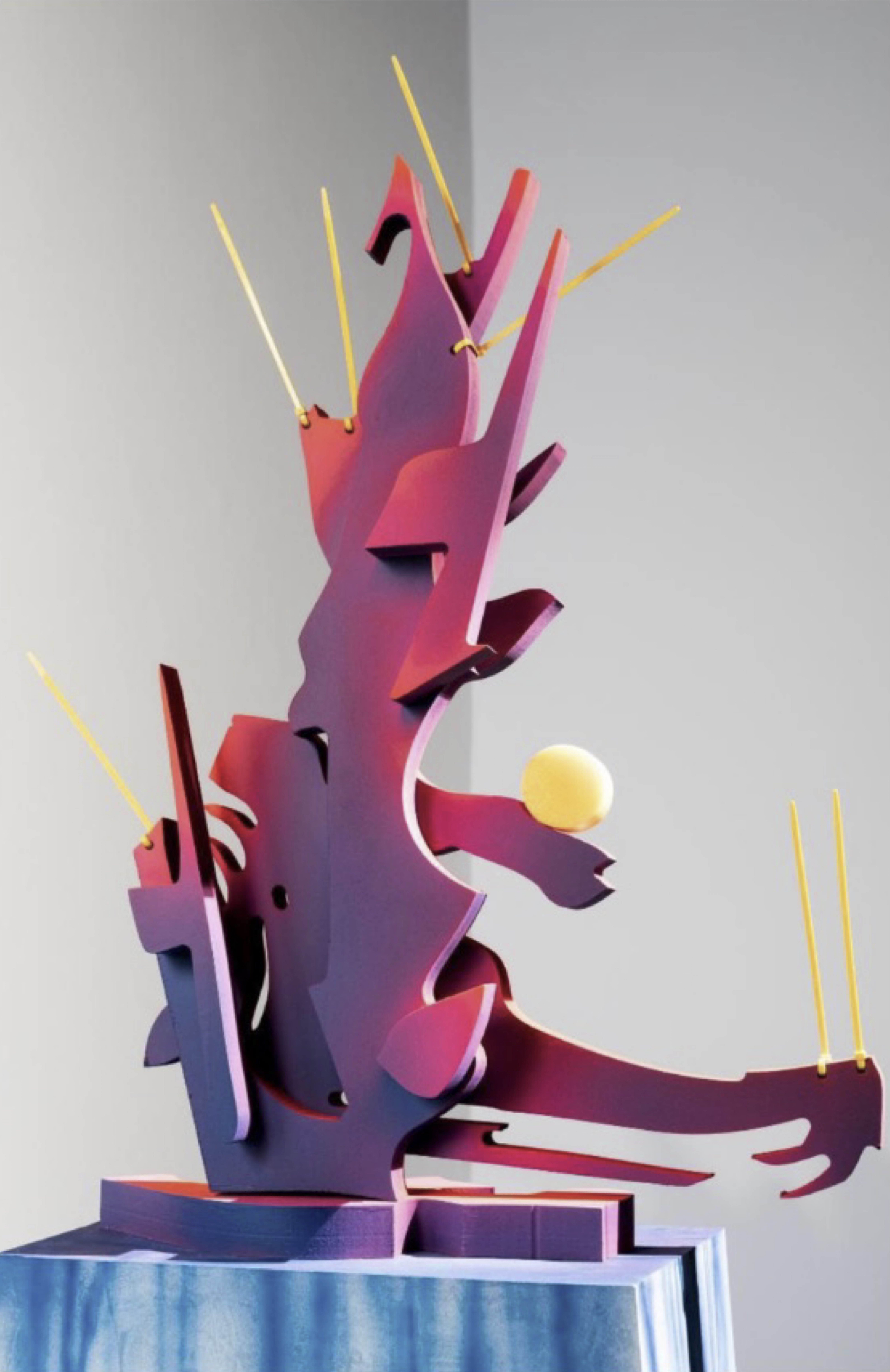 A sculpture of a man holding a tennis ball on a table.