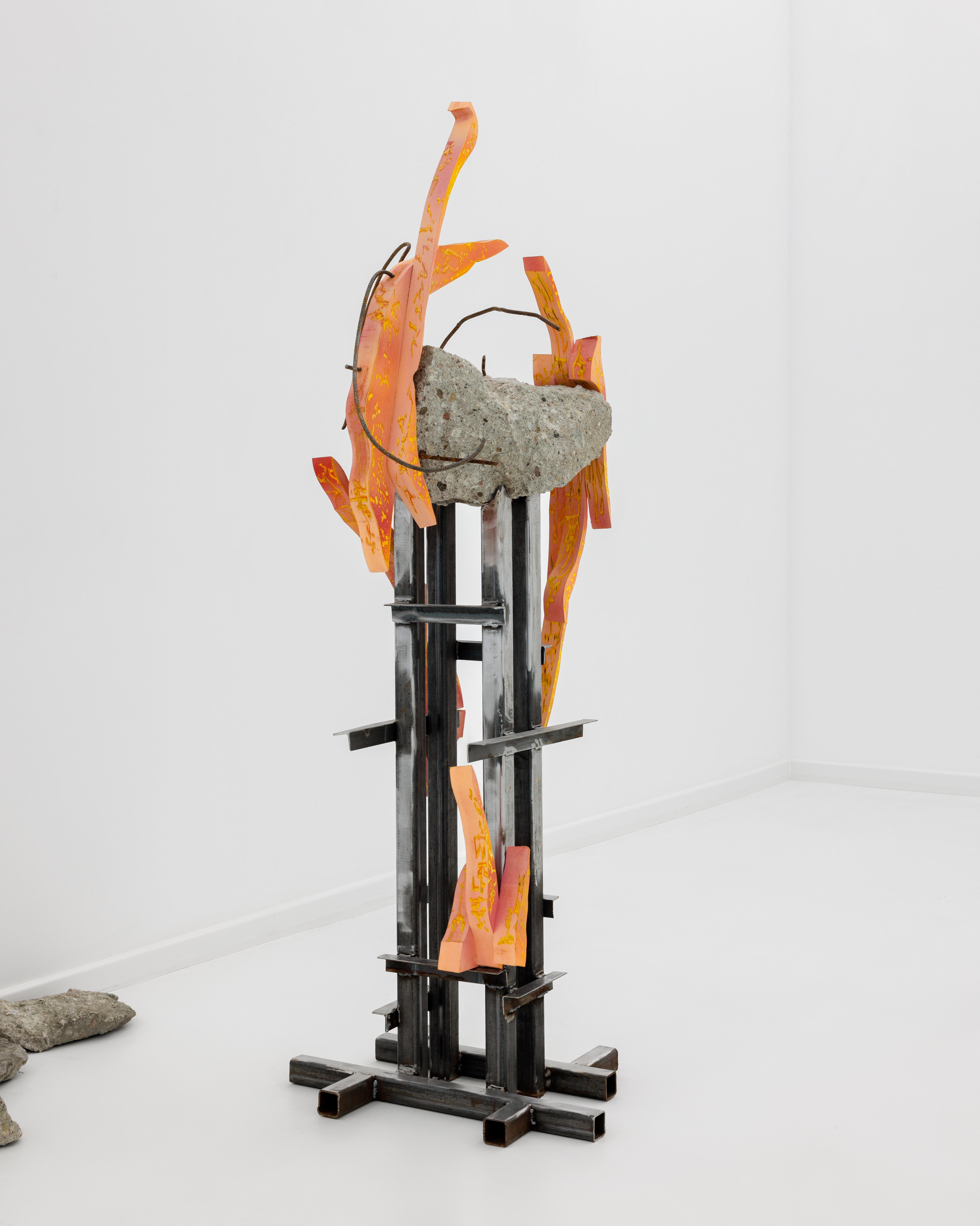 A sculpture on a metal stand in a white room.